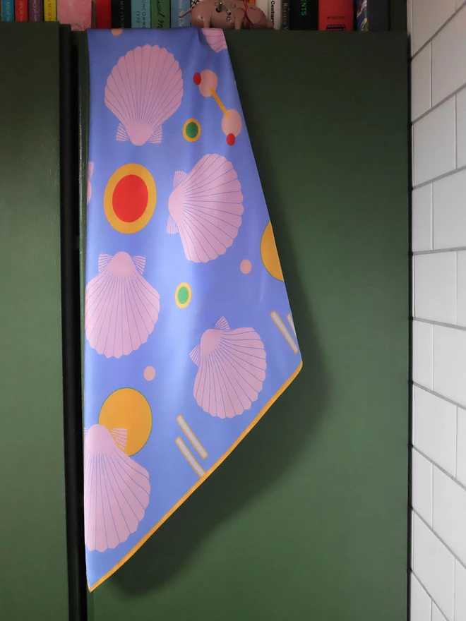 'Sea Shells - Blue and Pink' Silk Scarf hanging on the back of a wardrobe