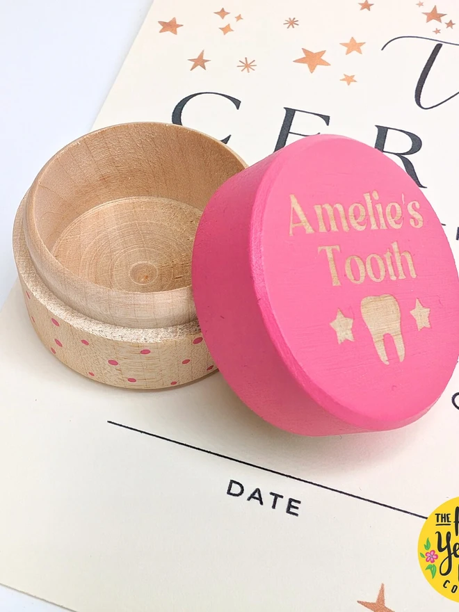 personalised wooden tooth fairy box. a round wooden box with a pink painted lid and personalised text.