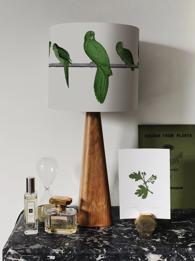 A colourful lampshade featuring a lively group of green parrots in a tropical jungle-inspired design, bringing a playful touch to home interiors.