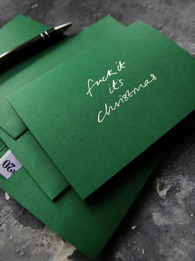 Hand foiled cash card or money wallet in a forest green colour handfoiled in shiny lime green text which says 'fuck it it's christmas'.