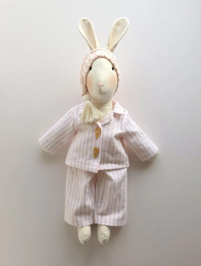Full-length handmade Veronica Bunny wearing pink striped brushed cotton pyjamas and a pale pink knitted Christmas Eve sleepy hat.
