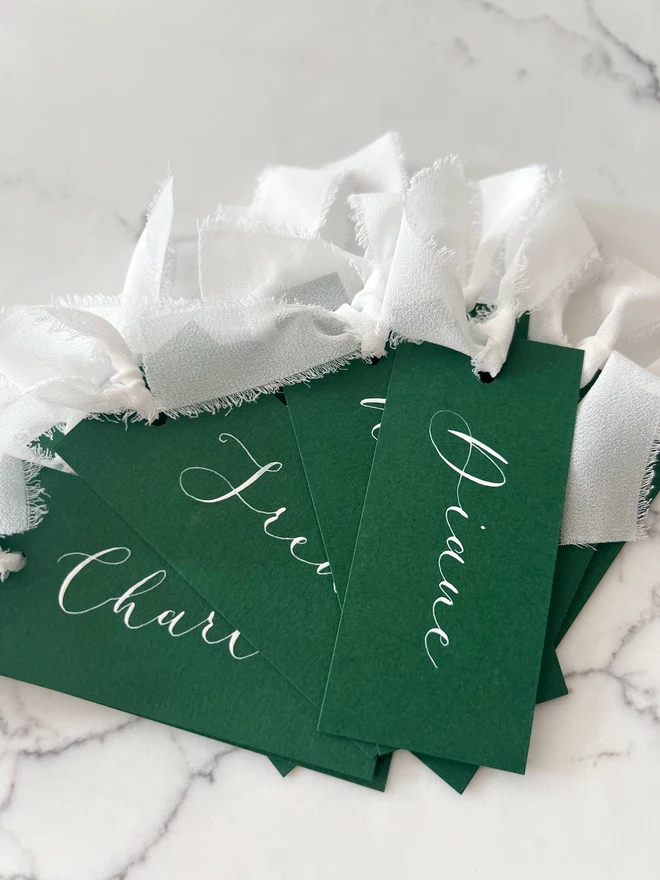Personalised Calligraphy Wedding Green Place Cards, grouped together with white ribbon. 