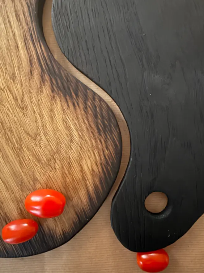 Close up showing the contrast between the boards one Yakisugi one lightly charred with scattered tomatoes 