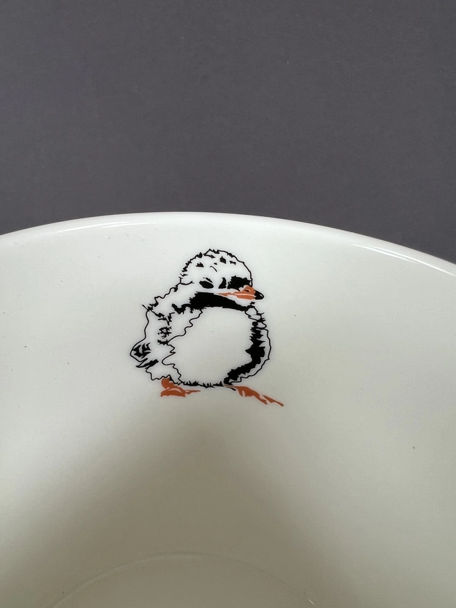 A close up image if the inside of the mug showing the fluffy cute baby puffin