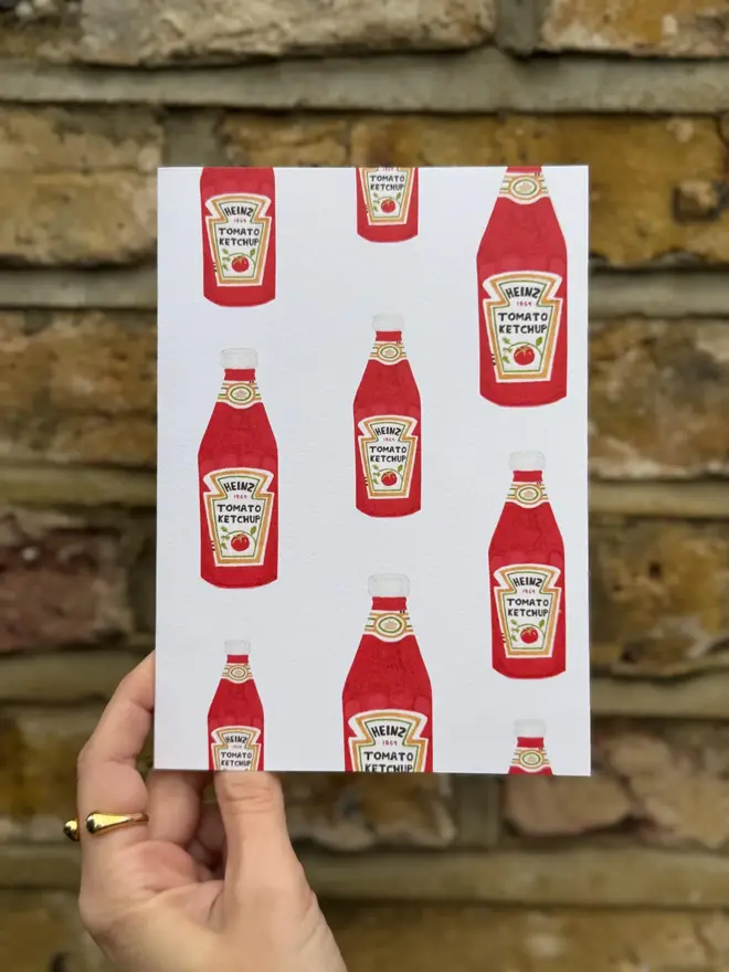 tomato ketchup bottles illustrated card. card photographed against brick wall backdrop. 