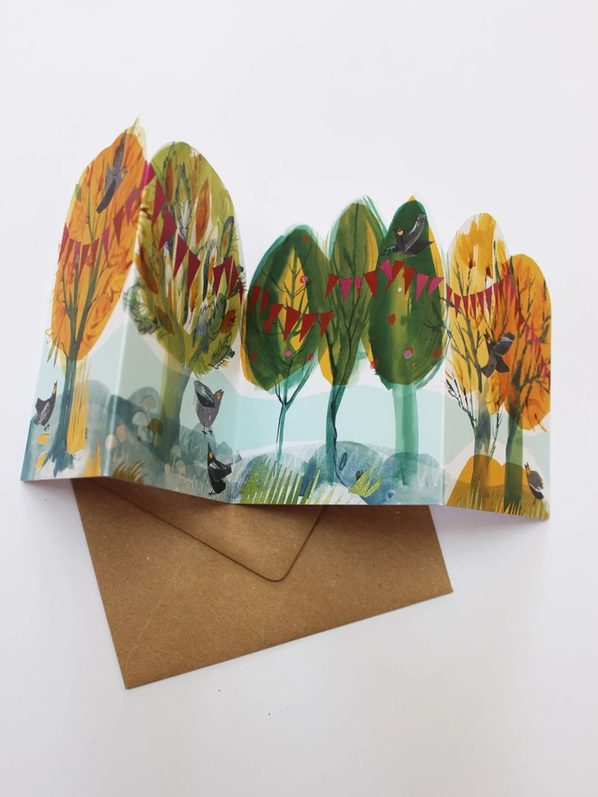 Flatlay showing concertina folded card of illustrated trees in green and yellow