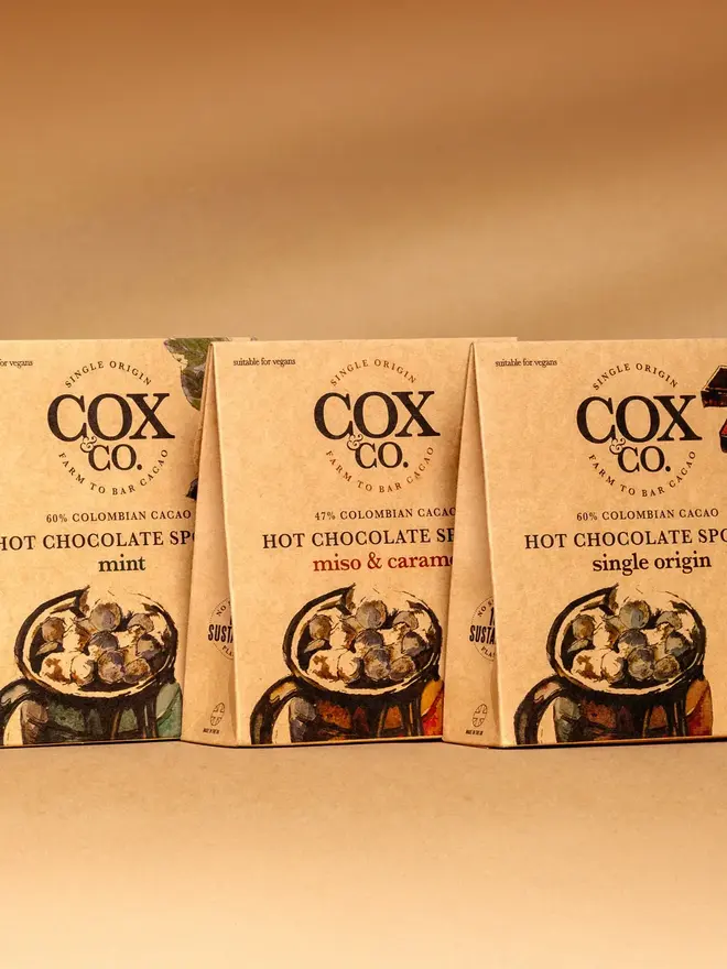 Cox&Co Mint Hot Chocolate Spoons (Set Of 3), a trio of hot chocolate spoon packages sitting on a colourful surface. 