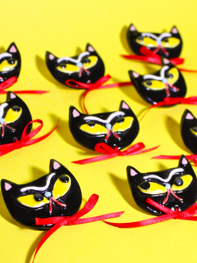 Spooky grumpy Black Cat Brooch with yellow eyes and red satin ribbon.