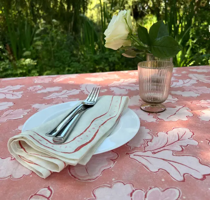 Grace Napkins (Set of 4). Light pink cloth napkin folded and displayed in a pink table cloth. 