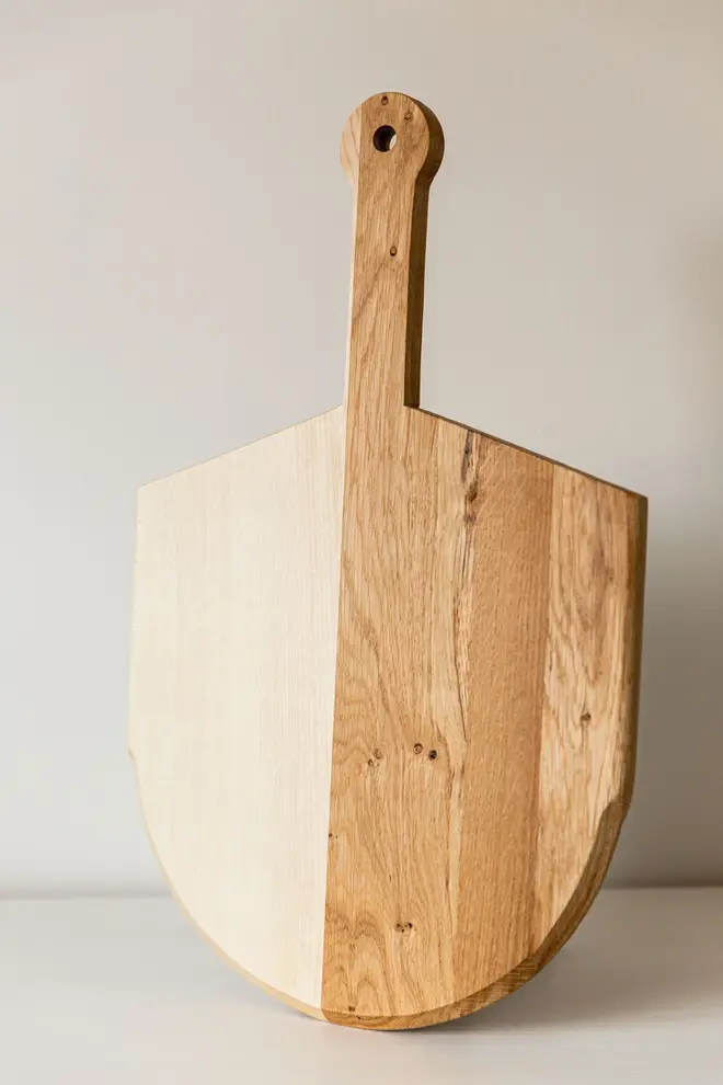 Pizza Board, a wooden pizza serving board sat on a white surface against a plain backdrop. 