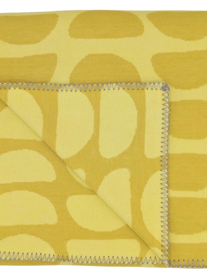 Organic Cotton Throw, a cotton throw folded into a square on a floor. 