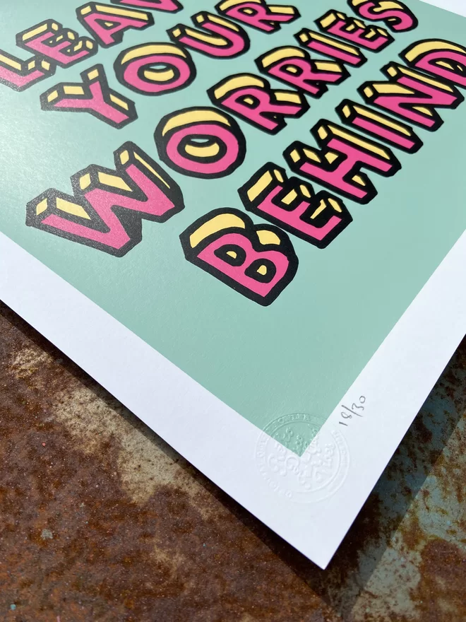 "Leave Your Worries Behind" Hand Pulled Screen Print on mint background square with hand drawn printed letters in pink on top that say leave your worries behind 