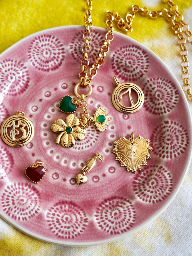 Gold and green lucky talisman charms on a pink artisan plate
