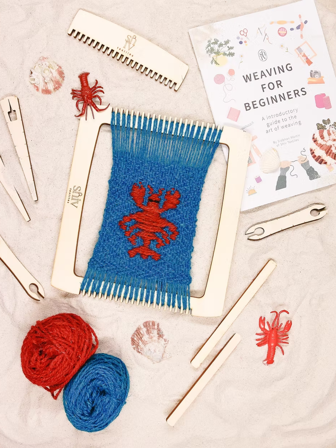 seaside weaving kit. a blue weave piece with a red lobster photographed on a loom.
