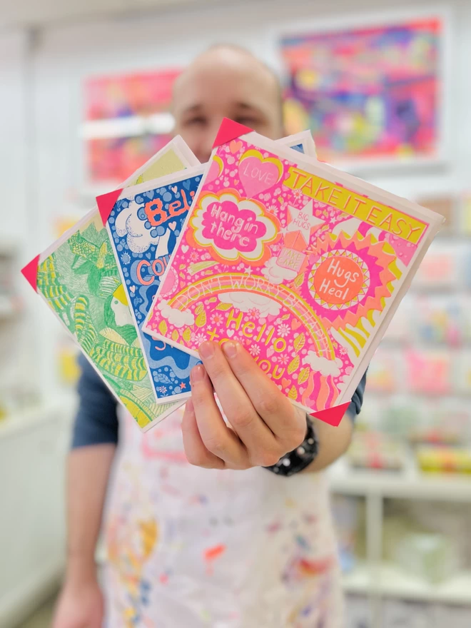 Artists holding Take it Easy card, a riso printed get well soon card showing messages of positivity