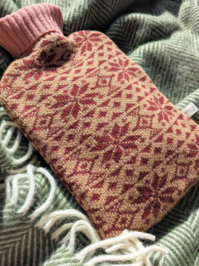 COLOURFUL HOT WATER BOTTLE COVER DISPLAYED ON A ON A BLANKET