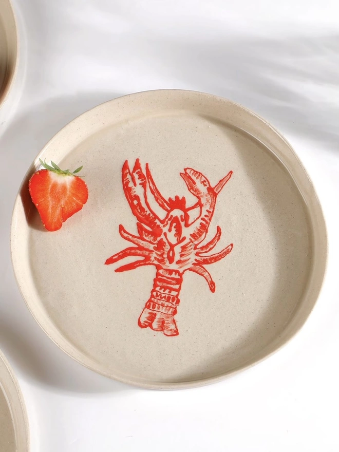 Handmade Ceramic Side Plate With Red Lobster Design, a side plate with a red lobster design on a white table. 