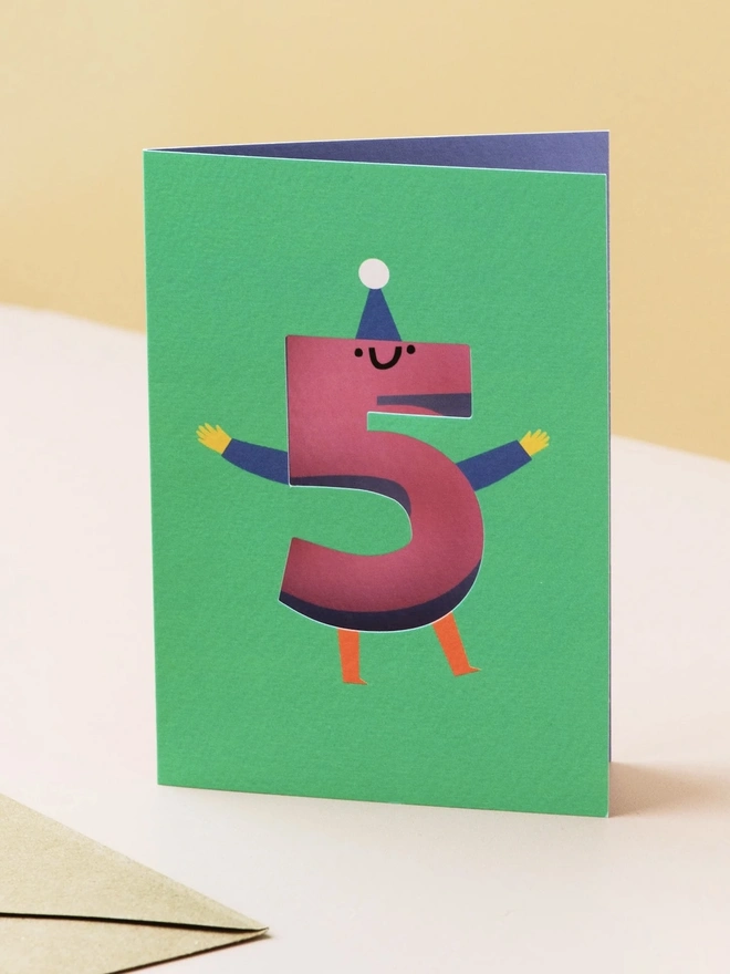 5th Birthday Card, on a table next to its brown envelope. 