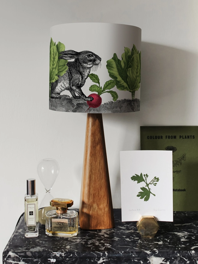 Mischievous rabbit lampshade handmade with vintage animal etchings, hiding among lettuces and radishes in a quirky country-style design. 