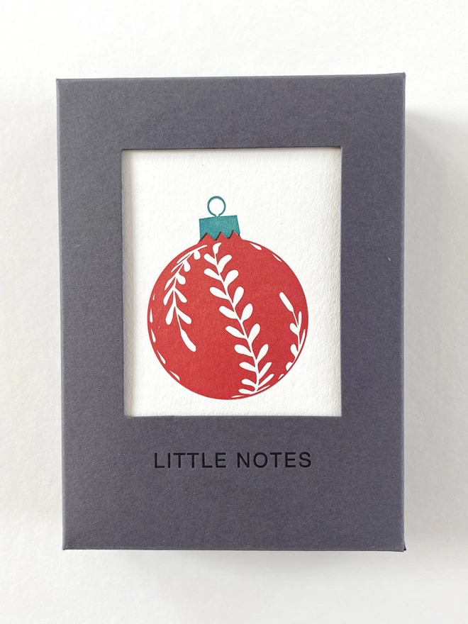Close up of the window on the gift boxes showing the red leaf Christmas bauble on little notes
