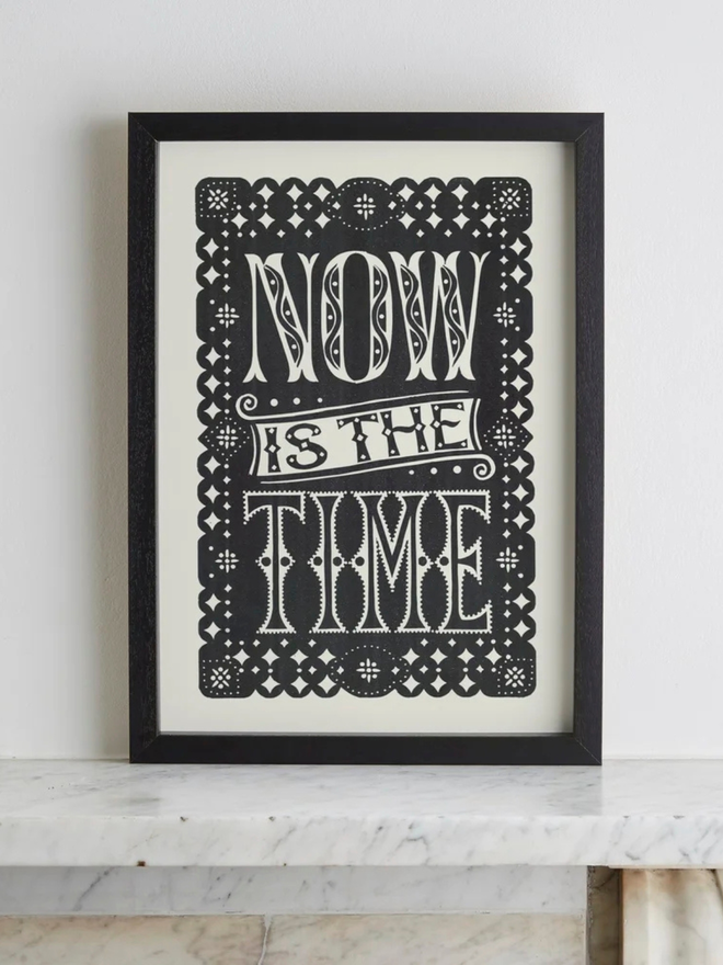 now is the time linocut. a linocut phrase printed on black paint.