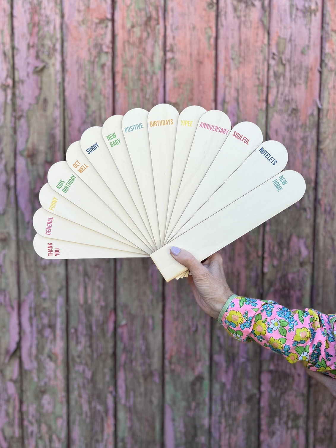 A number of wooden card dividers being held by an outstretched hand in a fan shape