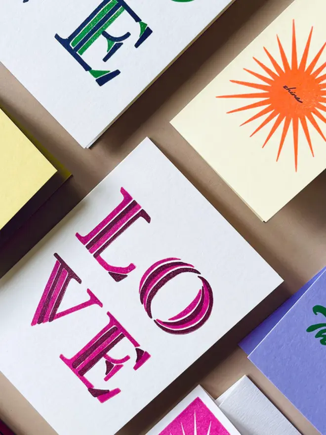 'Love' stripe hand printed card displayed on a table with other cards. 