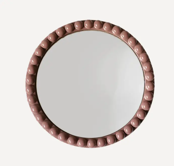 Round oversized bobbin mirror with a decorative bobbin-style wooden frame, hanging on a white wall.