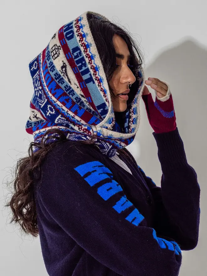 Model is wearing the fairisle loop scarf in klein with claret feminist mittens and our navy Do No Harm cardigan 