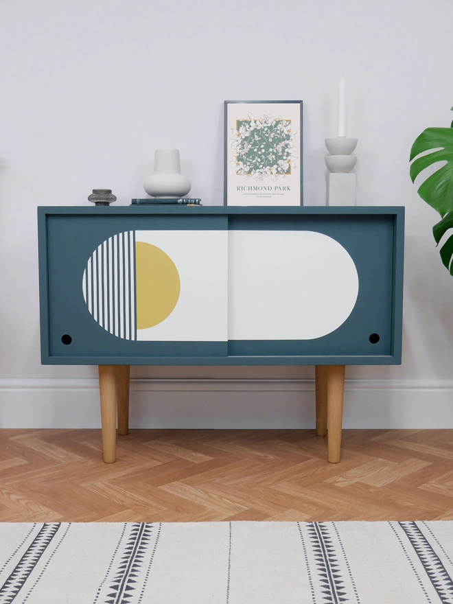 Teal Blue Mid Century Cupboard with Sliding Doors featuring bold geometric patterns in white and yellow