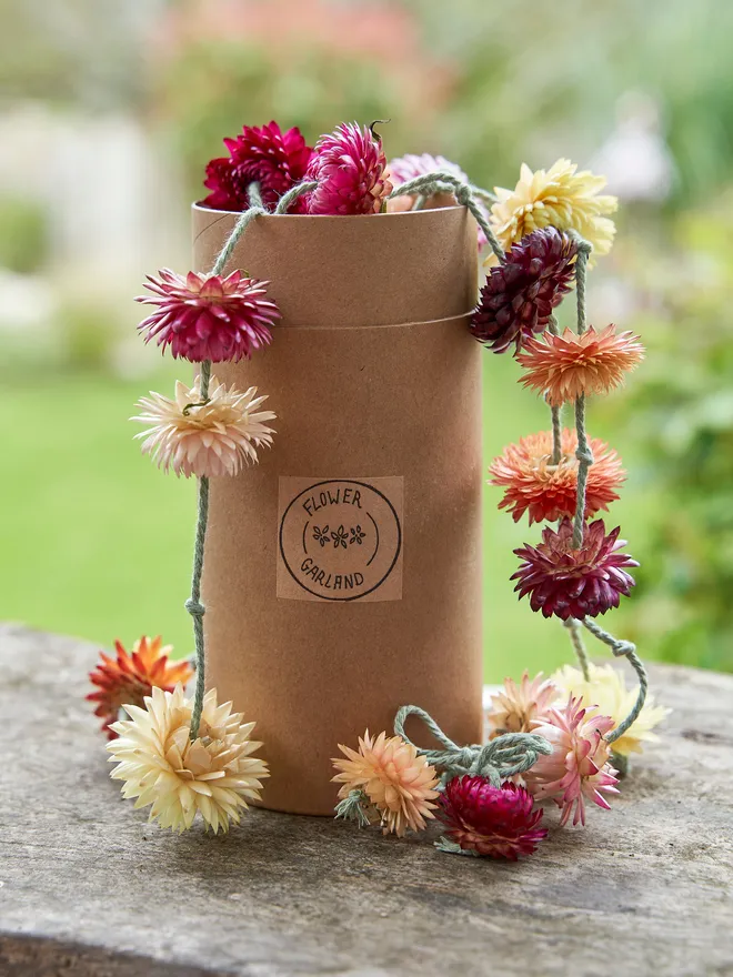 Rainbow dried flowers in a brown tube box on a wooden outdoor table in the garden 