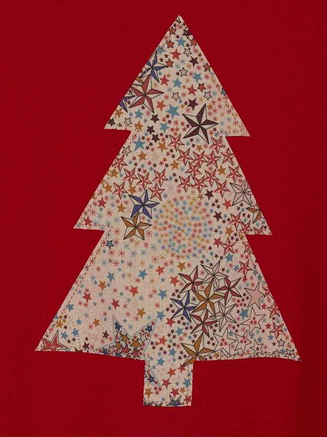 a close up of a red tee with a christmas tree cut from starry liberty print sewn onto the front
