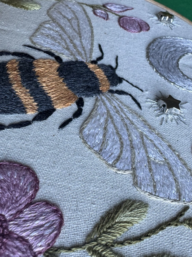 An embroidered bee surrounded by pink flower and silver stars