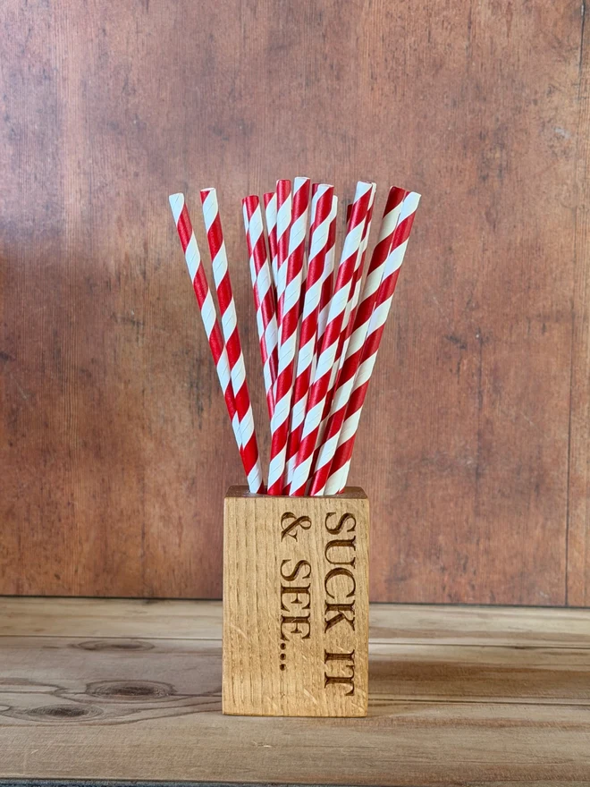 Stripy straws in a straw cup with engraving that says Suck it & see...
