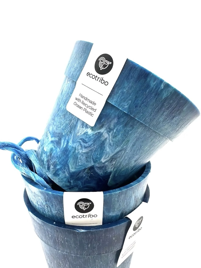 Small Blue Ocean Plastic Plant Pot , a collection of blue recycled pots sitting on a white surface against a plain backdrop. 