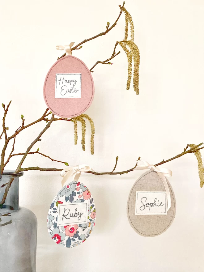 Selection of embroidered egg decorations hanging on a branch
