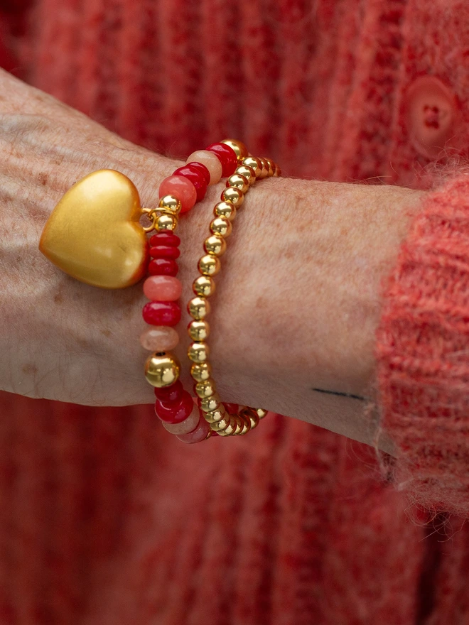 model wears The Bright Side Bead Bracelet in Romeo blends soft pink and vibrant red jade beads for a fresh, feel-good pop of colour. Hand-strung on durable stretch elastic and finished with a personalised charm of your choice, this stacking bracelet is designed for effortless everyday wear. A joyful handmade jade bead bracelet that brings colour, meaning, and brightness to every outfit.