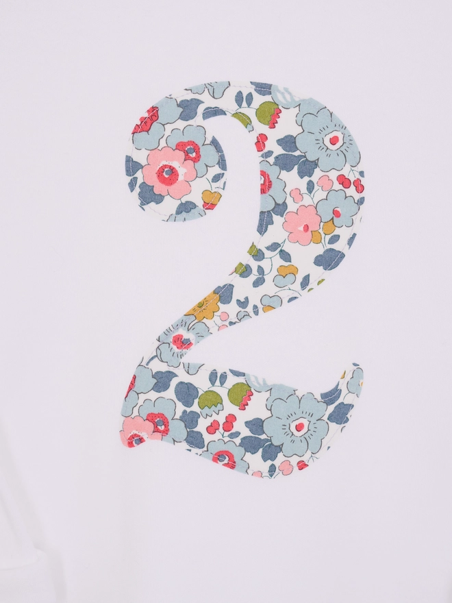 A close up of a white 2nd birthday t-shirt with a number 2 cut from liberty betsy floral print on the front
