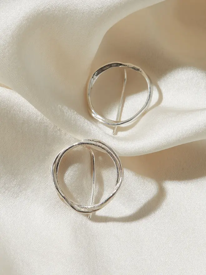 Two Silver Organic Circle Threader Earrings on a silk material