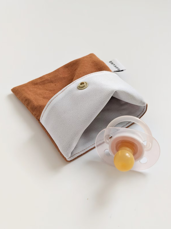 reusable linen snack pouch. a rust brown pouch holding a dummy.