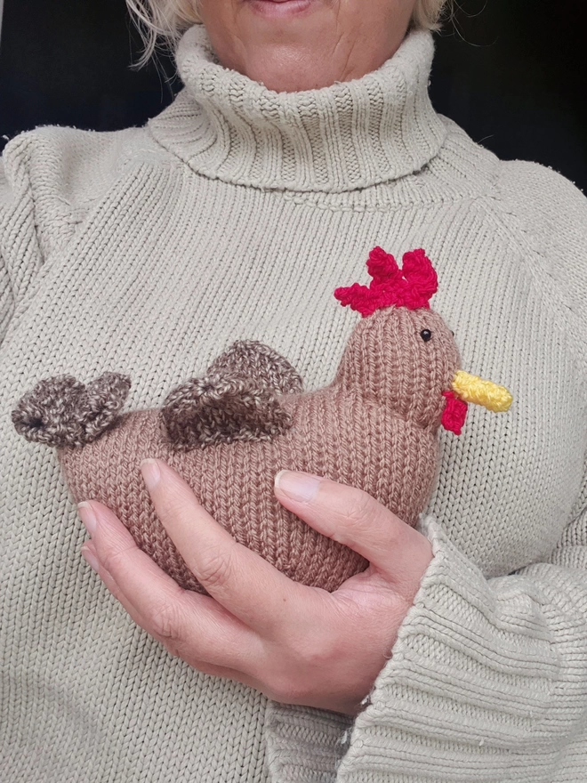 Henrietta the knitted brown hen having a cuddle