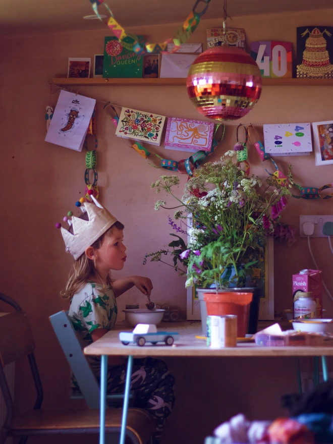Boy in gold birthday crown at breakfast table