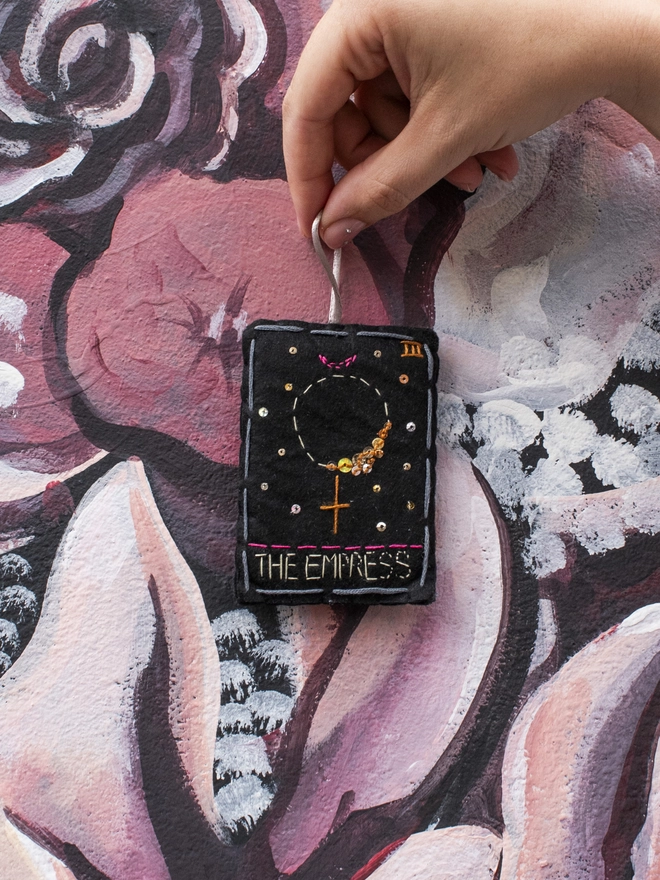 A handcrafted felt ornament with sequins and embroidery depicting "The Empress" tarot card. 