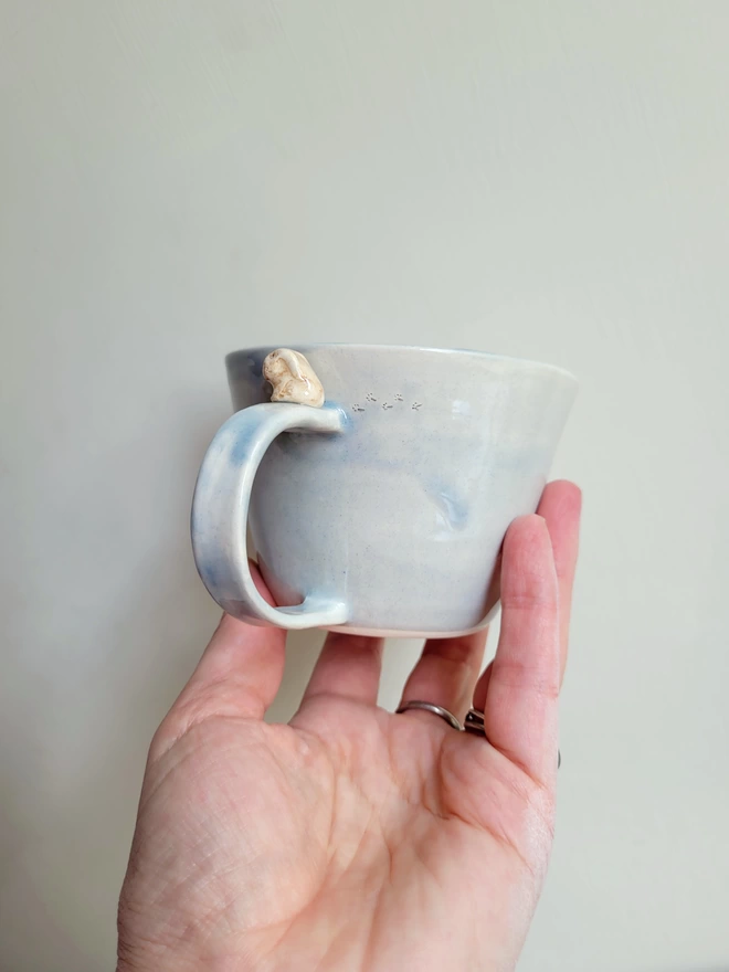 Ceramic grey coffee cup with beige bunny on the handle and foot prints
