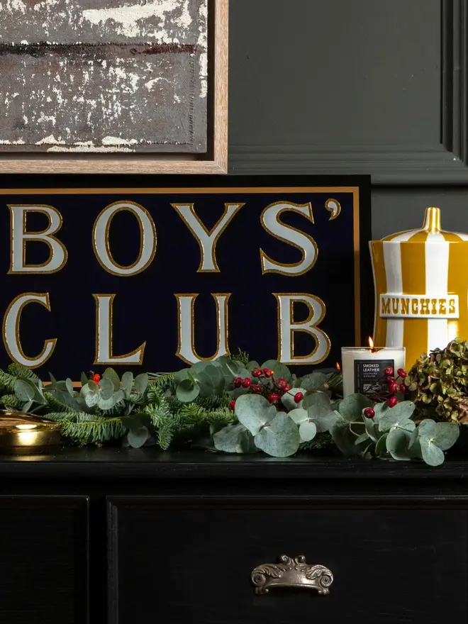 boys club hand painted sign. sign propped up on a mantelpiece.