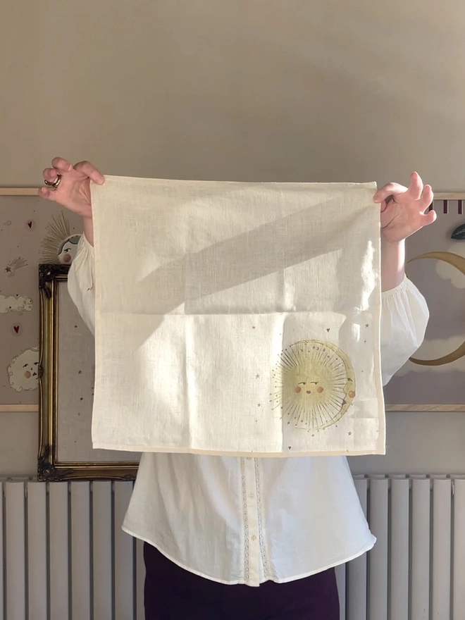 Celestial Linen Dinner Napkins (Set Of 2), a person holding a linen napkin with a sun motif. 