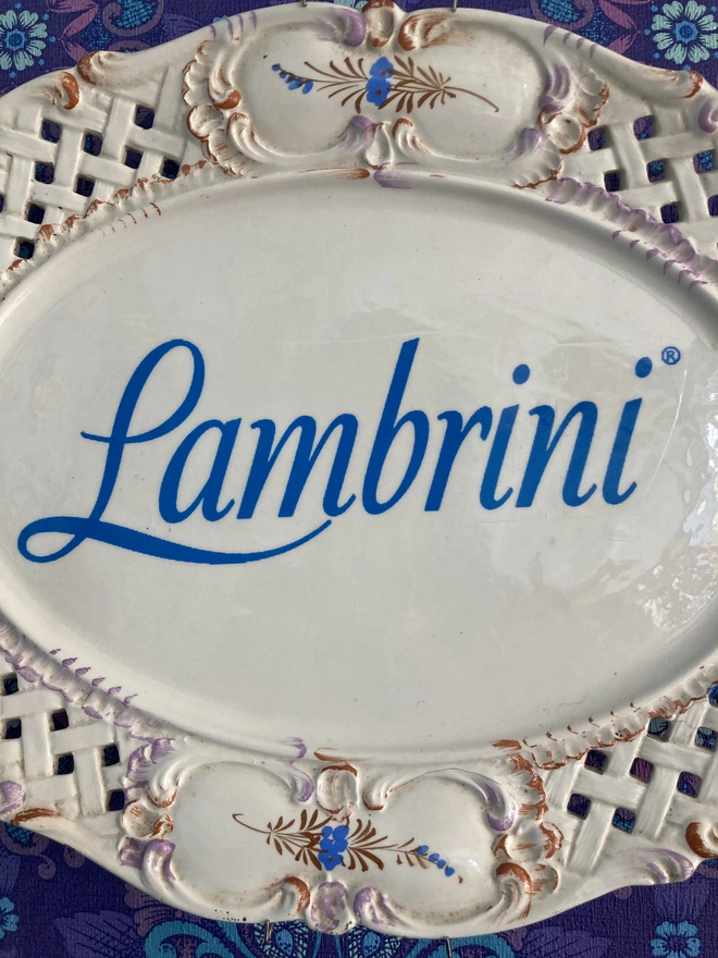 A close up of the Lambrini logo on the plate.