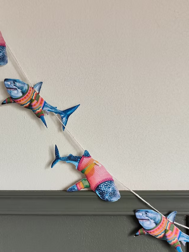 illustrated shark garland. sharks in jumpers on bunting hung up on a wall.