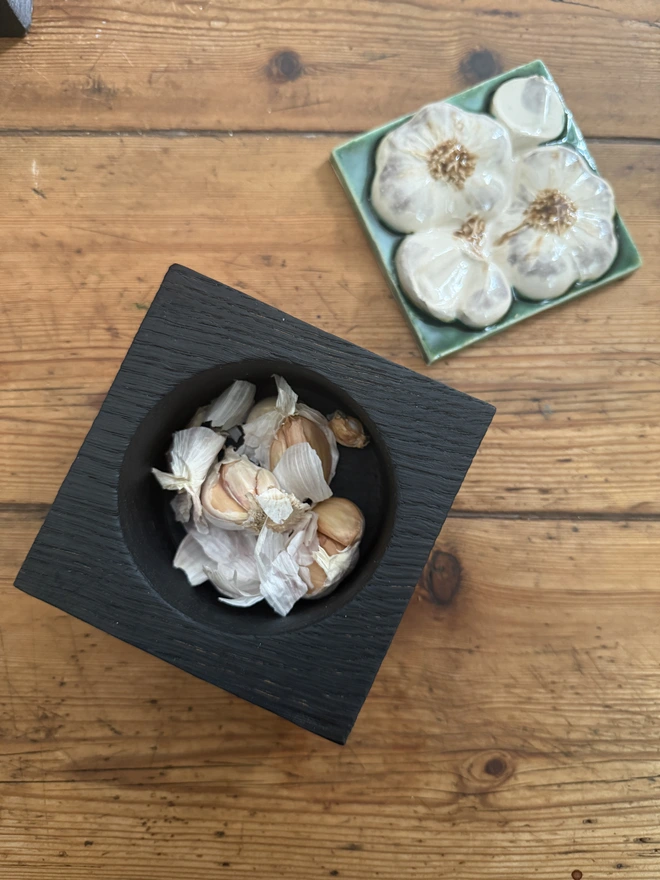 Charred black oak pots with ceramic garliic lid and garlic cloves in pot