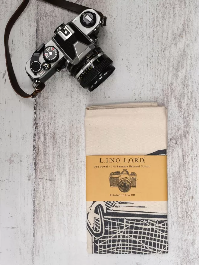 Picture of a tea towel with an image of a Camera, taken from an original lino print